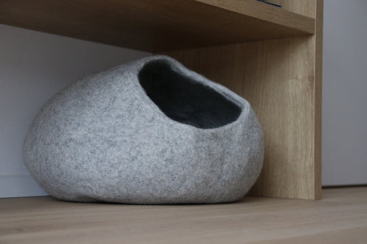Grey Nest merino wool felt cat bed beneath a wooden shelf
